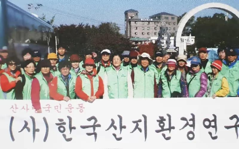 연구회 이름이 적힌 현수막 뒤로 녹색 조끼를 입은 산지정화활동 참가자 수십 명이 모여 있는 모습
