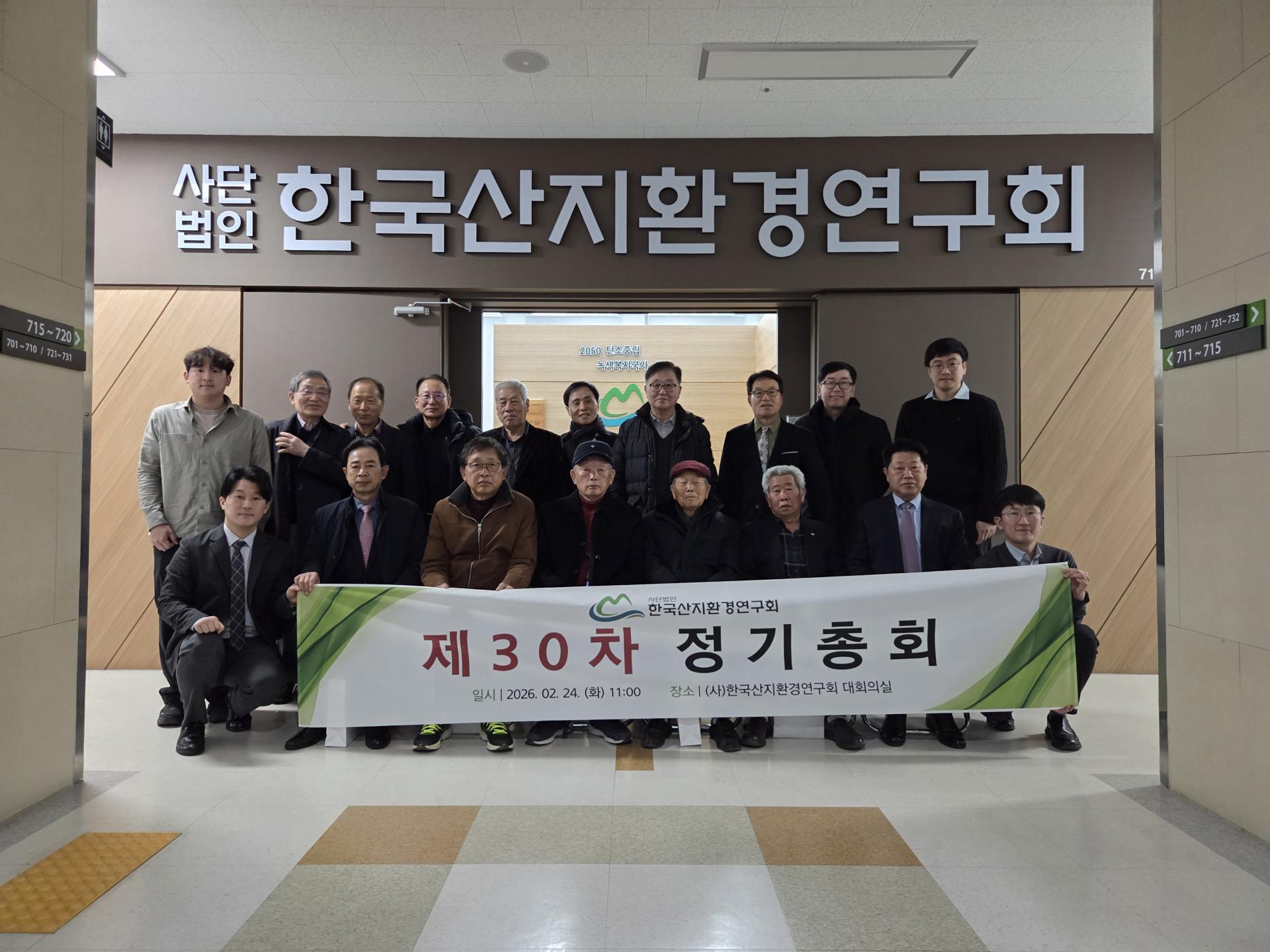제30차 정기총회를 마친 회원들이 현판 아래에서 현수막을 들고 단체로 기념하는 모습