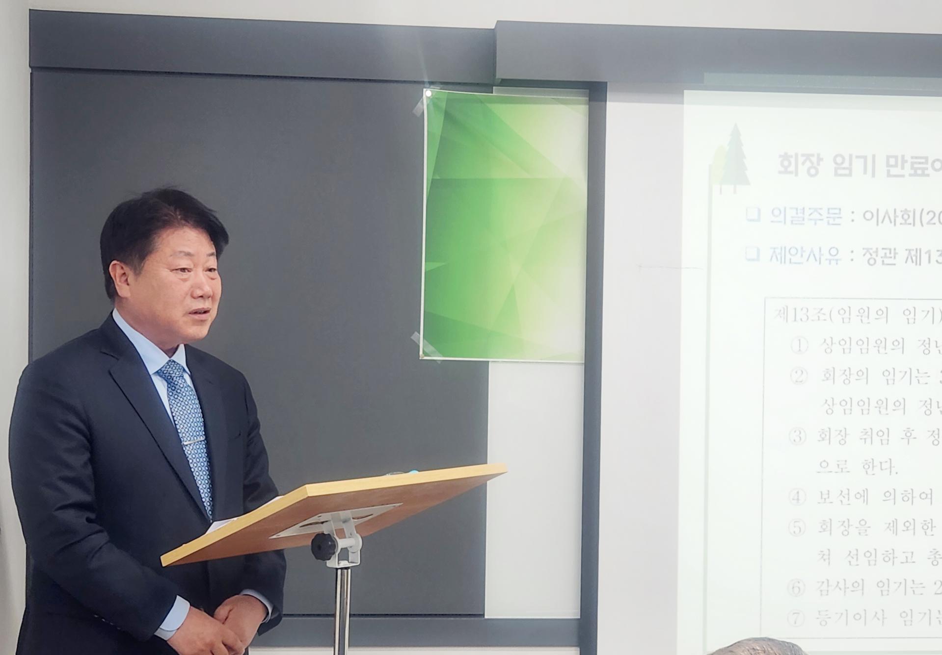 제28차 정기총회: 발표자가 단상에서 회장 임기 만료에 따른 정관 개정 안건을 설명하는 모습